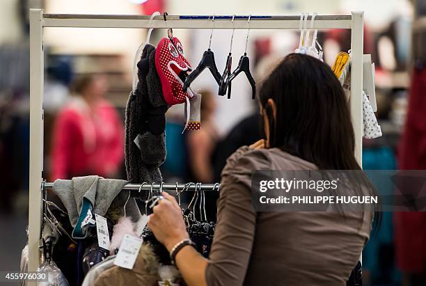 Customer looks at clothes in a shop of French clothing company Kiabi in Faches-Thumesnil, northern France, on September 23, 2014. AFP PHOTO /...