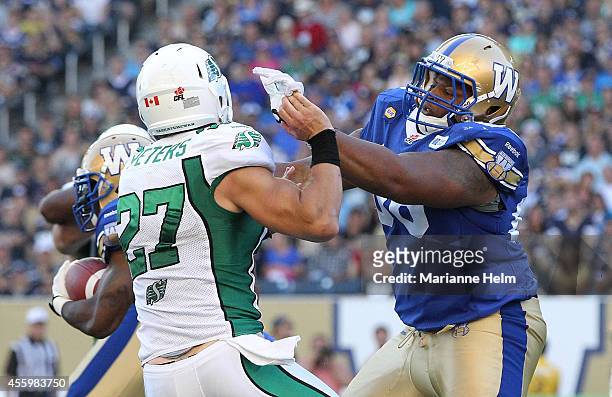 Cordaro Howard of the Winnipeg Blue Bombers keeps hold of Brian Peters of the Saskatchewan Roughriders in second half action in a CFL game at...