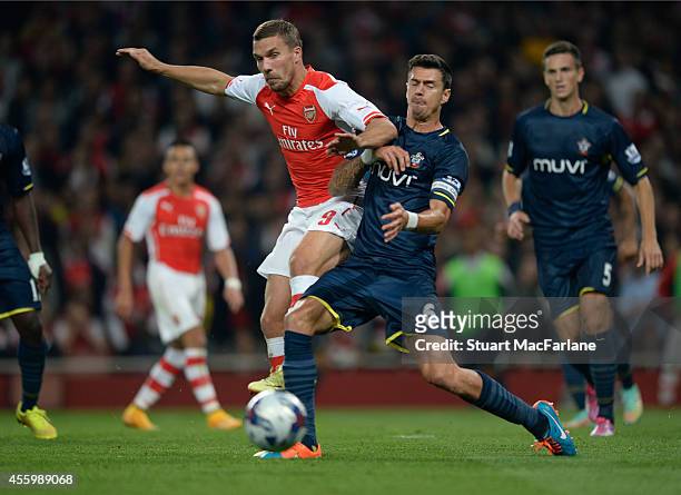 Lukas Podolski of Arsenal challenged by Jose Fonte of Southampton during the Capital One Cup Third Round match between Arsenal and Southampton at...