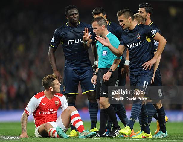 Jack Wilshere of Arsenal on the floor as the Victor Wanyama and Dusan Tadic of Southampton complain to Referee Keith Stroud during the Capital One...