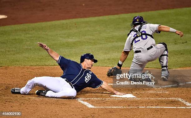 Tommy Medica of the San Diego Padres scores ahead of the throw to Wilin Rosario of the Colorado Rockies during the sixth inning of a baseball game at...