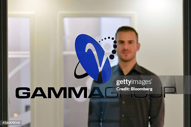 Martin J. Muench, managing director of Gamma International GmbH, stands behind the Gamma Group logo as he poses for a photograph in Munich, Germany,...