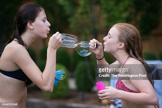 Eloise Lancsweert, 15 and Evie Wolfe, 13 blow bubbles during a barbecue at Greta De Keyser and Chef Bart Vandaele's home in Alexandria, Virginia on...