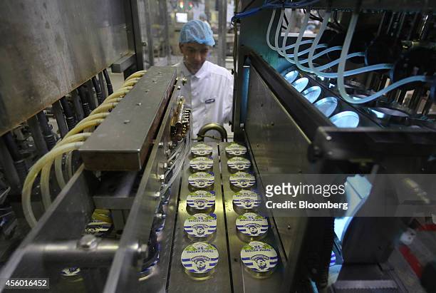 Worker watches as cartons of prostokvashino curd, a traditional Russian dairy product, pass through a machine at the Group Danone in Russia dairy...