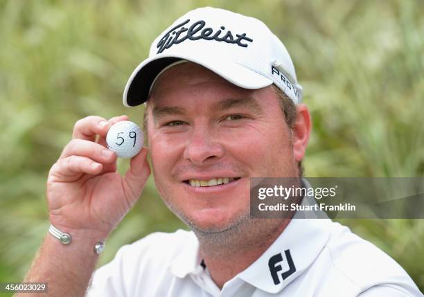 Colin Nel of South Africa holds his golf ball with the number 59 after shooting 59 during the weather delayed second round of the Nelson Mandela...