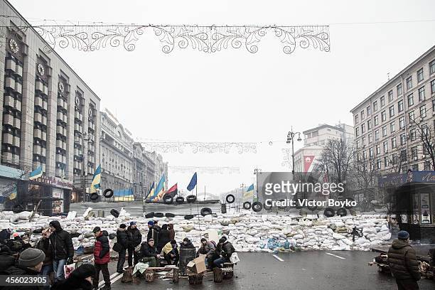 People stand near a barricade on Khreshchatyk street near Maidan Square on December 12, 2013 in Kiev, Ukraine. Thousands have been protesting against...