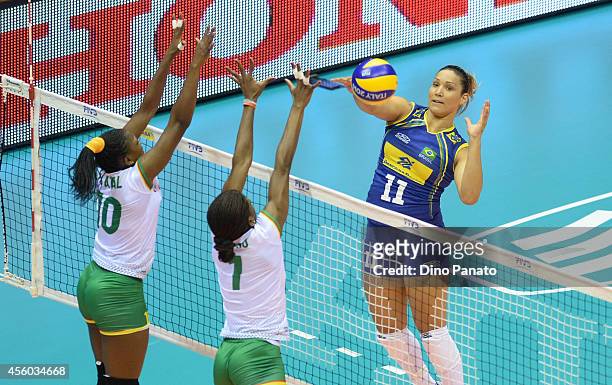 Tandara Caixeta of Brazil spikes the ball against to Berthrade Simone Flore Bikatal and Henriette Nadege Koulla of Cameroon during the FIVB Women's...