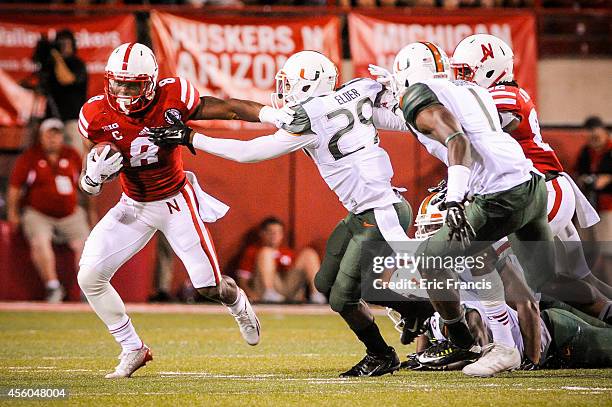 Running back Ameer Abdullah of the Nebraska Cornhuskers slips past defensive back Corn Elder of the Miami Hurricanes during their game at Memorial...