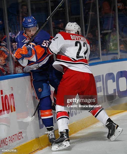 Aaron Ness of the New York Islanders is hit into the boards by Zach Boychuk of the Carolina Hurricanes during the first period at the Nassau Veterans...