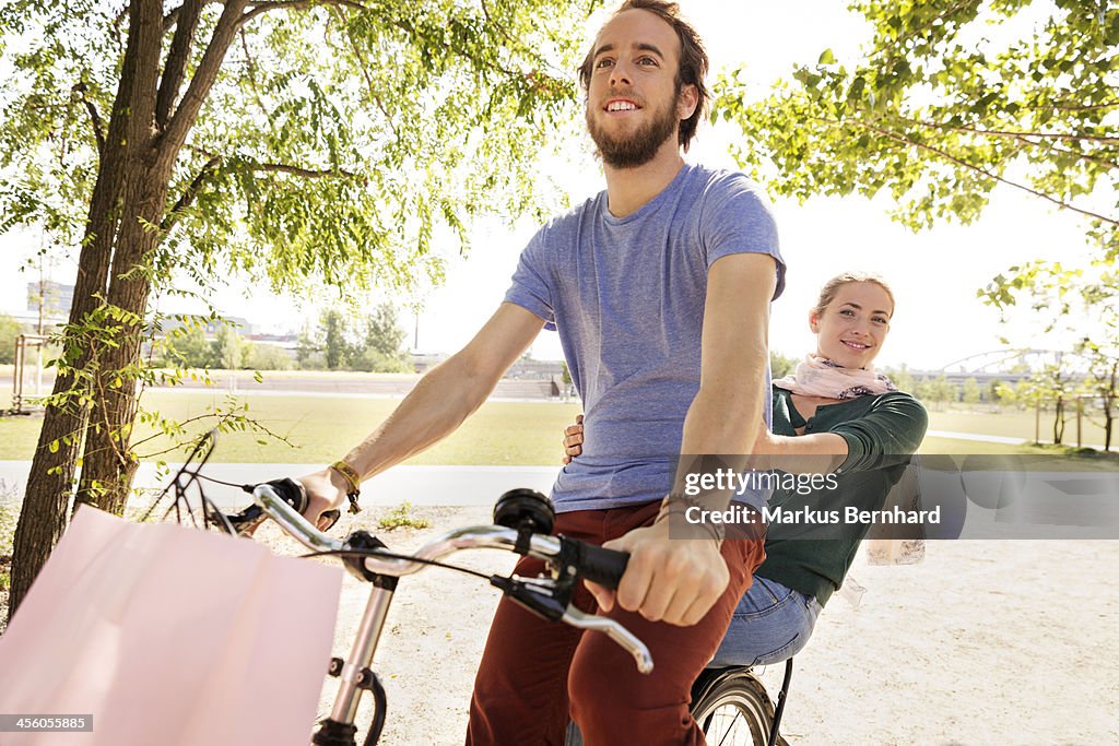 Couple share a ride on their bicycle.