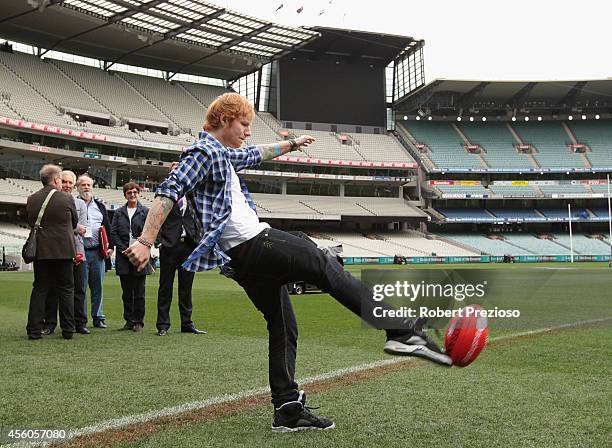 Ed Sheeran kicks a football after a press conference ahead of the AFL Grand Final at Melbourne Cricket Ground on September 25, 2014 in Melbourne,...