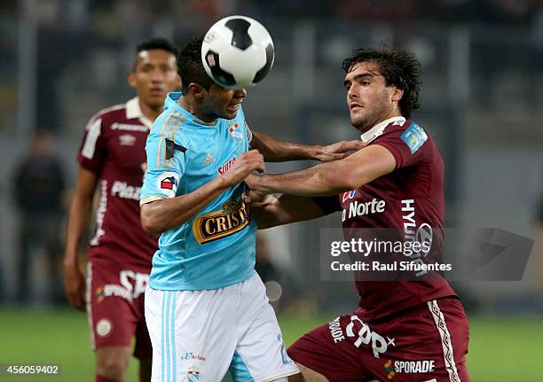 Carlos Lobaton of Sporting Cristal struggles for the ball with Alvaro Ampuero of Universitario during a match between Sporting Cristal and...