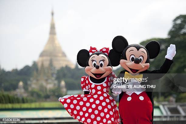 Walt Disney characters Mickey Mouse and Minnie Mouse pose for photographs in front of the Shwedagon Pagoda in Yangon on September 25, 2014. The...