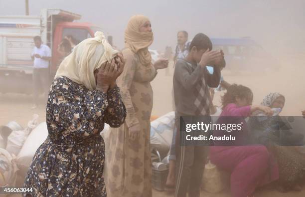 Zarife, a 85 year old Syrian Kurd, closes her eyes with her hands during a sandstorm as she waits at the border line for her relatives' arrival in...