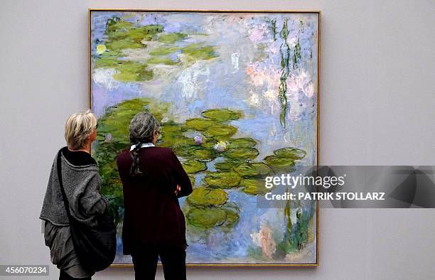 Visitors look at a painting Nympheas by French painter Claude Monet displayed in the exhibition "Monet, Gauguin, van Gogh... Inspiration Japan" at...