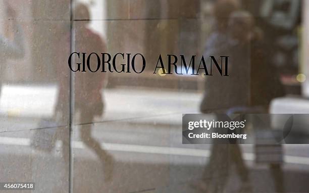 Pedestrians are reflected in the window of a Giorgio Armani SpA luxury store as they walk along Sloane Street in London, U.K., on Wednesday, Sept....