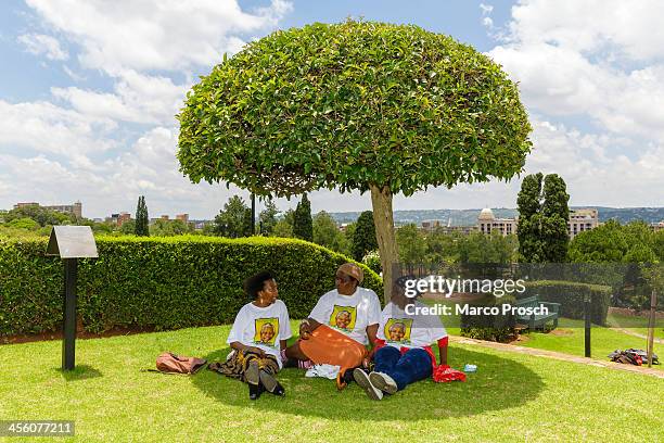 Visitors rest under a tree after paying respect to the body of former South African President Nelson Mandela lying in state at the Union Buildings on...