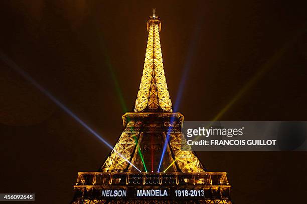 The words "Nelson Mandela, 1918 -2013" and light beams of colors of the South African national flag are seen on the illuminated Eiffel Tower on...