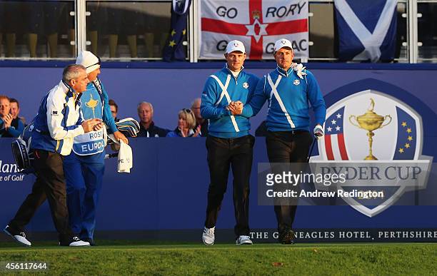 Justin Rose and Henrik Stenson of Europe shake hands as they leave the 1st tee, encouraged by Europe team captain Paul McGinley during the Morning...