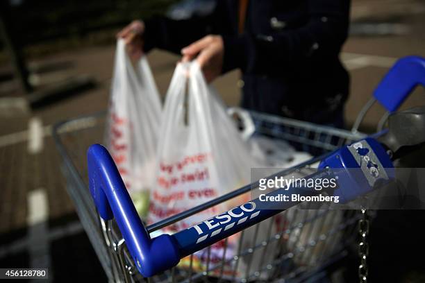 Customer removes her purchases from a shopping cart outside a Tesco Extra supermarket store, operated by Tesco Plc, in this arranged photograph taken...