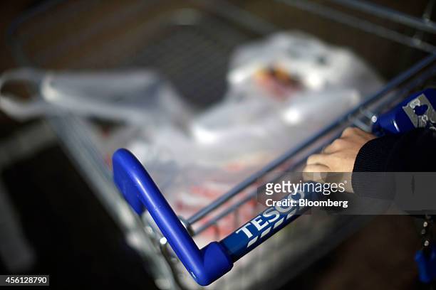 Customer pushes her purchases in a shopping cart outside a Tesco Extra supermarket store, operated by Tesco Plc, in this arranged photograph taken in...