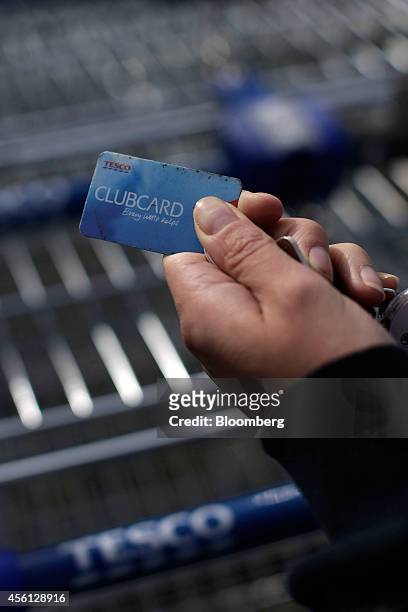Shopper holds their Clubcard rewards card near a shopping cart outside a Tesco Extra supermarket store, operated by Tesco Plc, in this arranged...