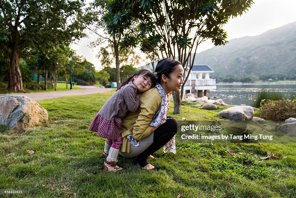 Toddler girl resting her head on mom's back