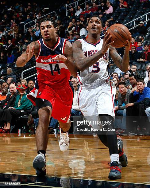 Louis Williams of the Atlanta Hawks drives against Glen Rice Jr. #14 of the Washington Wizards at Philips Arena on December 13, 2013 in Atlanta,...