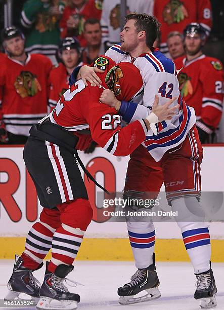 Dylan Mcllrath of the New York Rangers pulls the jersey over the head of Pierre-Cedric Labrie of the Chicago Blackhawks as they fight during a...