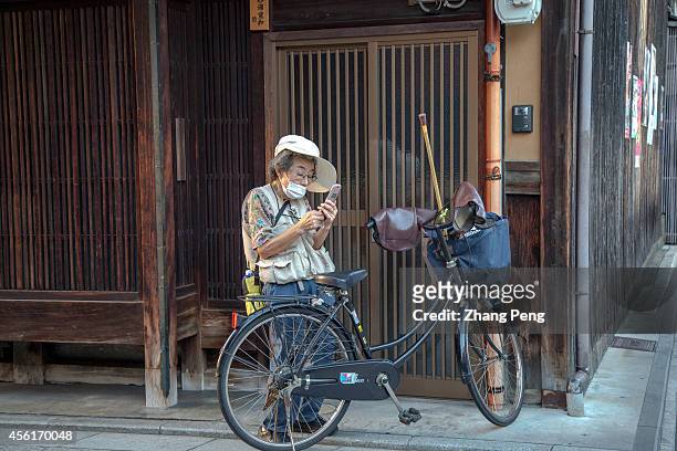 An old woman stops her bike and reads short message on her mobile phone. The number of people aged 65 or older in Japan will top a record 32.9...