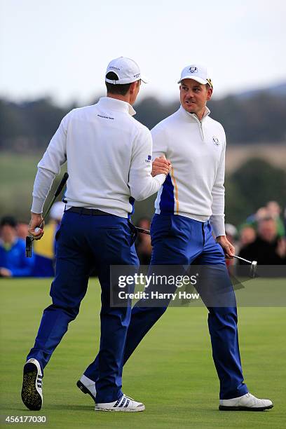 Henrik Stenson of Europe congratulates Justin Rose after his putt to win the 8th hole during the Morning Fourballs of the 2014 Ryder Cup on the PGA...