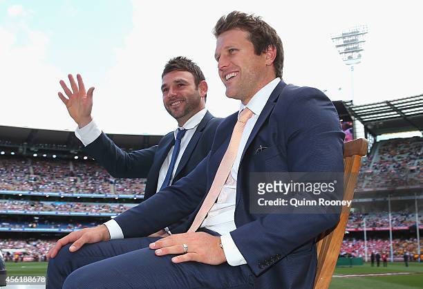 Brent Guerra of the Hawks and Campbell Brown of the Suns wave to the crowd during the Retiring Players Motorcade before the start of the 2014 AFL...