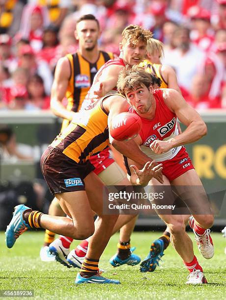 Nick Smith of the Swans handballs whilst being tackled by Cyril Rioli of the Hawks during the 2014 AFL Grand Final match between the Sydney Swans and...