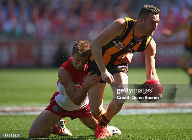 Matt Suckling of the Hawks handballs whilst being tackled by Kieren Jack of the Swans during the 2014 AFL Grand Final match between the Sydney Swans...