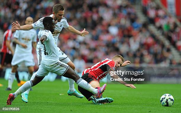 Swansea players Nathan Dyer and Gylfi Sigurdsson challenge Sebastian Larsson of Sunderland during the Barclays Premier League match between...