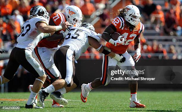 Running back Marshawn Williams of the Virginia Tech Hokies breaks an attempted tackle from defensive lineman Nick Matich of the Western Michigan...