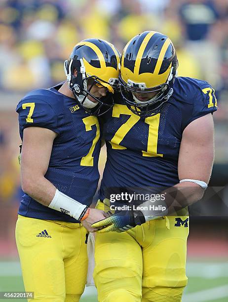 Quarterback Shane Morris of the Michigan Wolverines is helped off the field by Ben Braden during the fourth quarter of the game against the Minnesota...