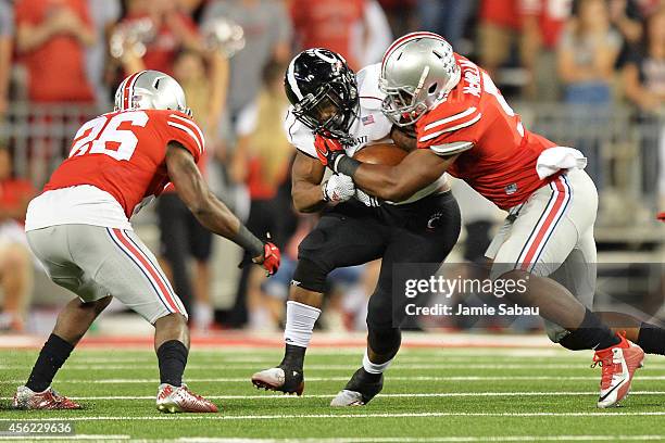 Hosey Williams of the Cincinnati Bearcats is wrapped up after a short gain by Armani Reeves and Raekwon McMillan of the Ohio State Buckeyes in the...