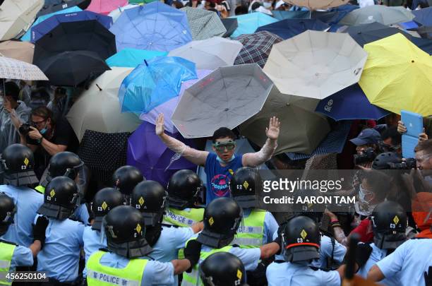 Pro-democracy demonstrator gestures in front of a police line near the Hong Kong government headquarters on September 28, 2014. Police fired tear gas...