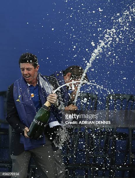 Rory McIlroy of Northern Ireland sprays champagne on stage after Team Europe retained the Ryder Cup trophy on the final day of the Ryder Cup golf...