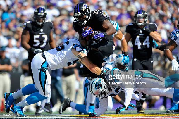 Running back Justin Forsett of the Baltimore Ravens is tackled by outside linebacker A.J. Klein of the Carolina Panthers and cornerback Melvin White...
