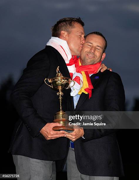 Ian Poulter of Europe kisses Sergio Garcia as they pose with the Ryder Cup trophy after the Singles Matches of the 2014 Ryder Cup on the PGA...