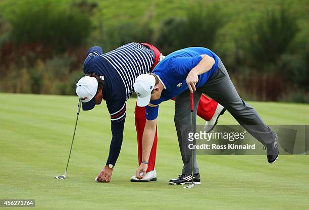 Phil Mickelson of the United States and Stephen Gallacher of Europe mark their balls on the 15th green during the Singles Matches of the 2014 Ryder...