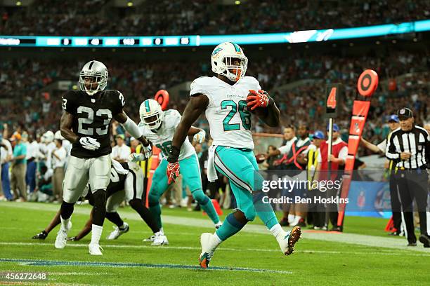 Lamar Miller of the Miami Dolphins scores his team's second touchdown on a nine yard rush during the NFL match between the Oakland Raiders and the...