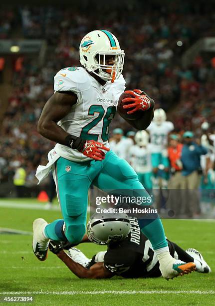 Lamar Miller of the Miami Dolphins scores his team's second touchdown on a nine yard rush during the NFL match between the Oakland Raiders and the...