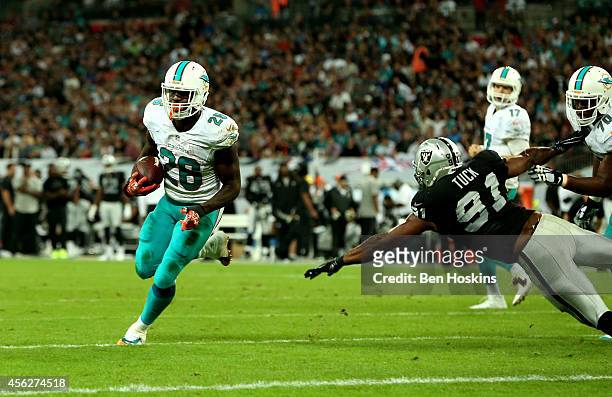 Lamar Miller of the Miami Dolphins scores his team's fourth touchdown on a one yard run during the NFL match between the Oakland Raiders and the...