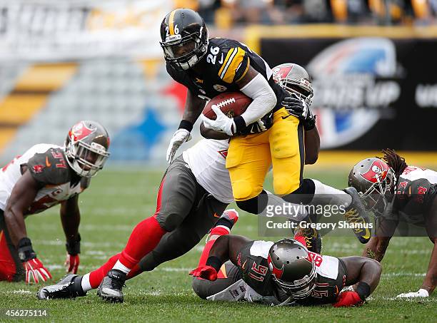 Le'Veon Bell of the Pittsburgh Steelers carries the ball in front of the defense of Clinton McDonald and Da'Quan Bowers of the Tampa Bay Buccaneers...