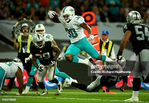 Daniel Thomas of the Miami Dolphins is tap tackled by Usama Young of the Oakland Raiders during the NFL match between the Oakland Raiders and the...