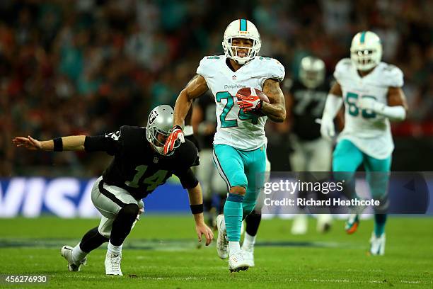 Cortland Finnegan of the Miami Dolphins returns a fumble 50 yards to score a touchdown during the NFL match between the Oakland Raiders and the Miami...