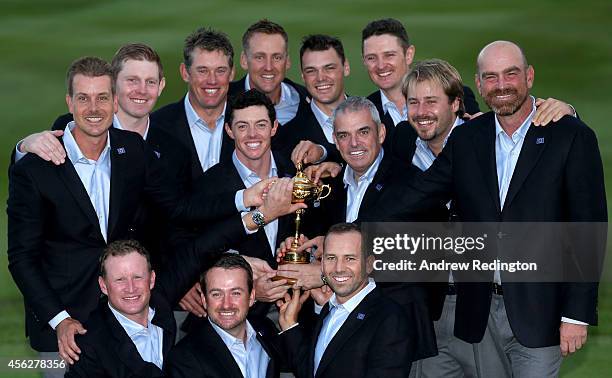 Europe team captain Paul McGinley and Rory McIlroy of Europe pose with the Ryder Cup trophy and team mates after the Singles Matches of the 2014...